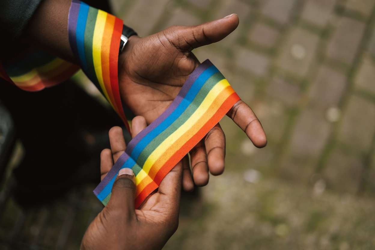 Crop unrecognizable black man showing LGBT ribbon on hand